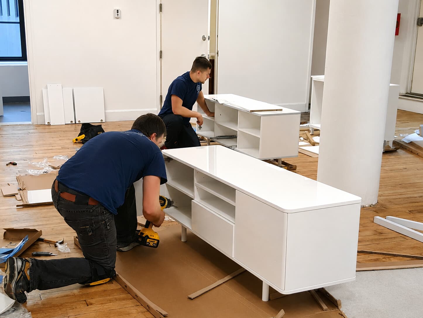 Two-person crew assembling a large media console together